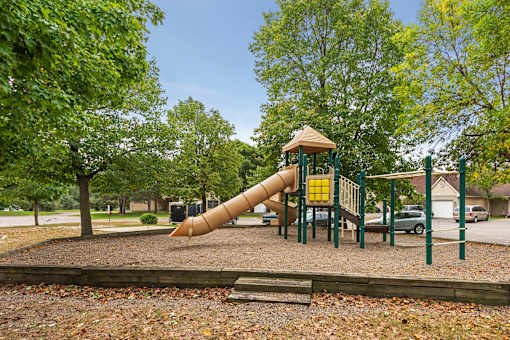 A playground with a yellow slide and a brown roof.