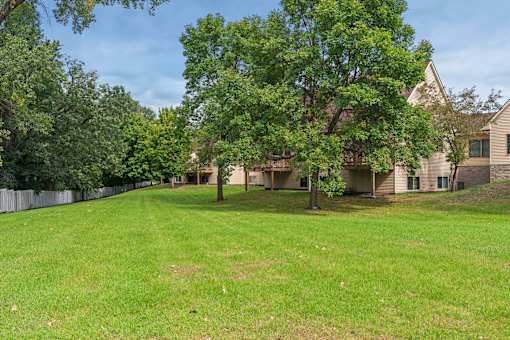 A large grassy area with trees and houses in the background.