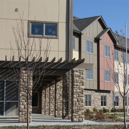 A building with a stone pillar and a tree in front.