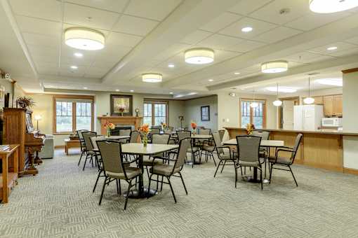 A large room with tables and chairs and a piano.