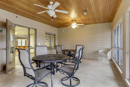 A patio with a table and chairs and a ceiling fan.