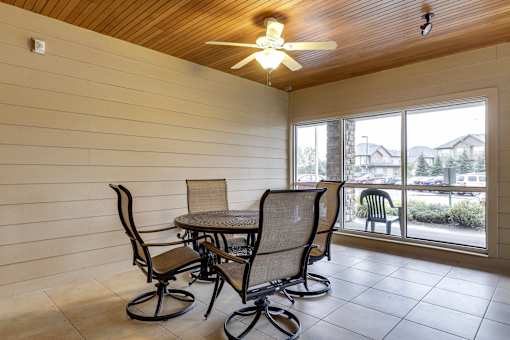 A table with four chairs is in a room with a ceiling fan.