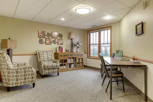 A room with a desk, chairs, and bookshelves.
