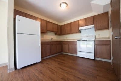 A kitchen with white appliances and wooden cabinets.