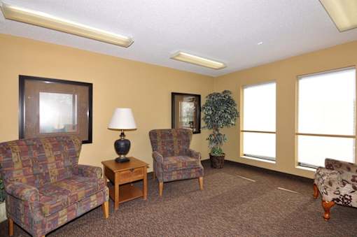 A living room with two chairs, a table with a lamp, and a couch.