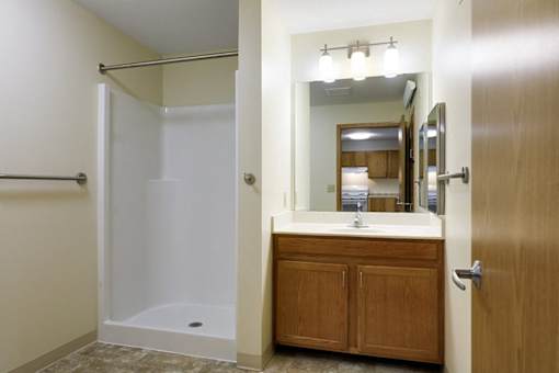 A bathroom with a white tub and a wooden medicine cabinet.