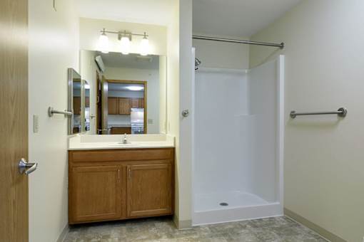 A bathroom with a wooden vanity and a walk-in shower.