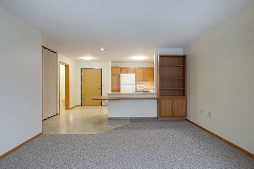 A kitchen area with a white counter and wooden cabinets.