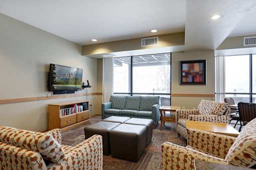 A living room with a couch, chairs, and a television.