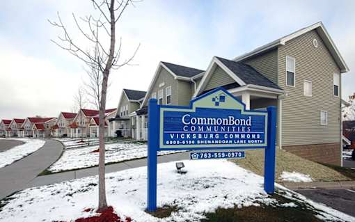 A sign for CommonBond Communities stands in front of a house.