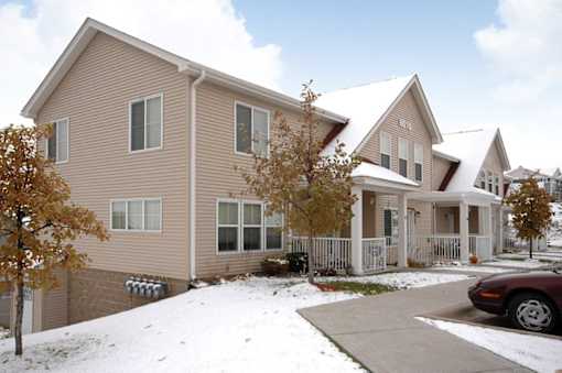 A beige house with a white fence and a car parked in front.