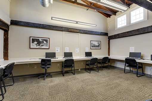 A room with a long table and chairs with a picture on the wall.