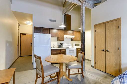 A kitchen with a table and chairs in the foreground and a refrigerator in the background.