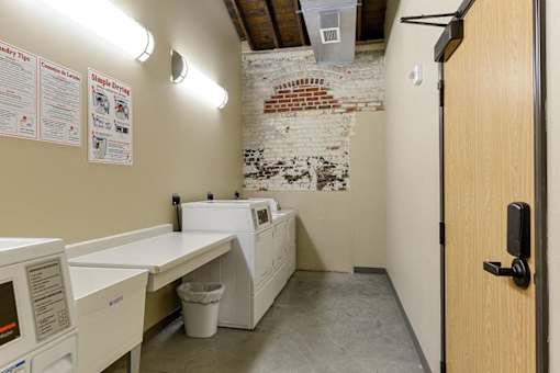 A room with a white washing machine and a trash can.