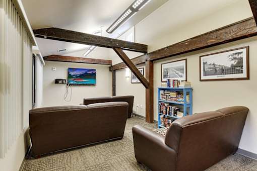 A room with a brown couch and a blue bookshelf.