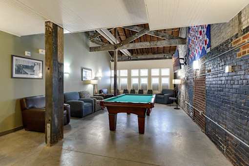 A room with a pool table and leather chairs.
