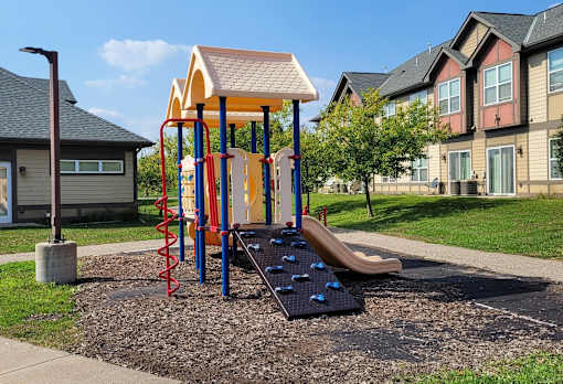 A playground with a slide, swings, and a climbing wall.