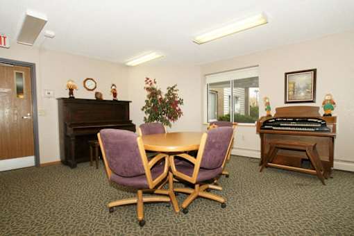 A conference room with a table, chairs, and a piano.