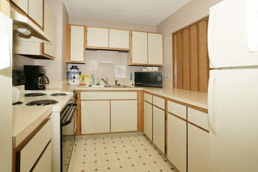 A kitchen with white appliances and wooden cabinets.