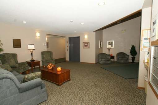 A living room with a grey sofa, a wooden coffee table, and a lamp on a side table.