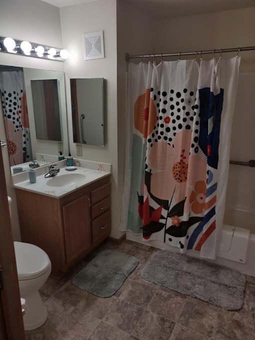 A bathroom with a toilet, sink, mirror, and shower curtain.