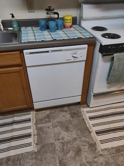 A white dishwasher is in a kitchen next to a white oven.