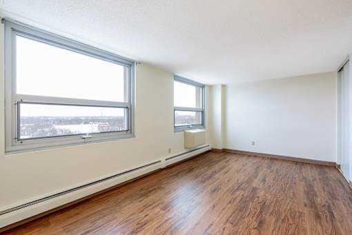 A room with wooden floors and two windows.