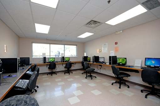 A room with multiple computer workstations and chairs.