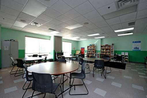 A room with tables and chairs and a bookshelf.