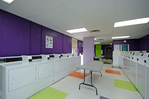 A laundromat with washers and dryers lined up on both sides of the room.