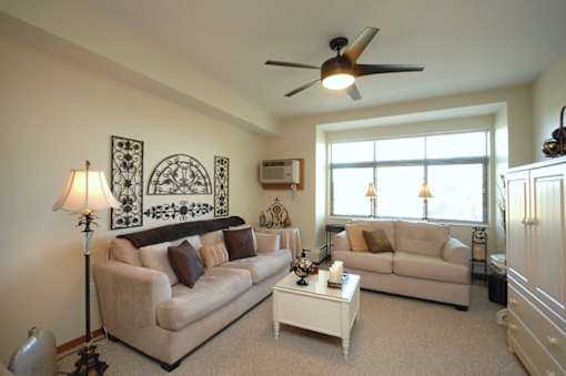 A living room with a beige couch, a white coffee table, and a ceiling fan.