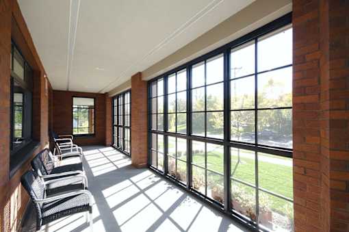 A sunny day in a room with a row of chairs and a brick wall.