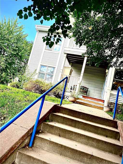 A set of stairs with a blue railing lead up to a house.