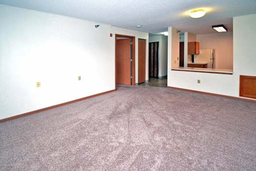 A carpeted room with a door and a mirror on the wall.