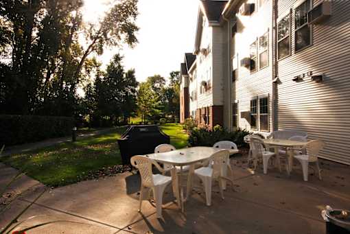 A patio with a white table and chairs is set up outside a building.