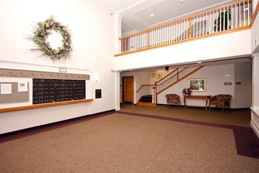 A hallway with a wreath on the wall and a staircase.