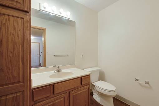 A bathroom with a toilet, sink, and mirror.