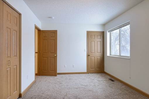 A room with two brown doors and a window.