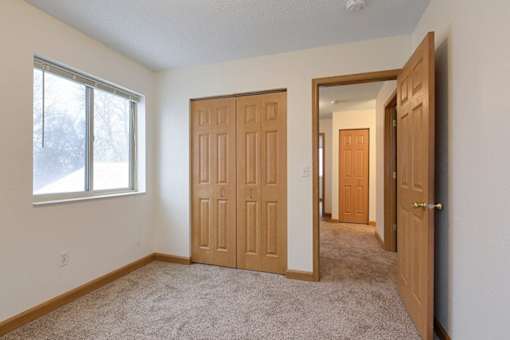 A room with a carpeted floor and two wooden doors.