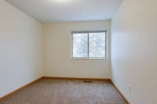 A room with a window and carpeted floor.