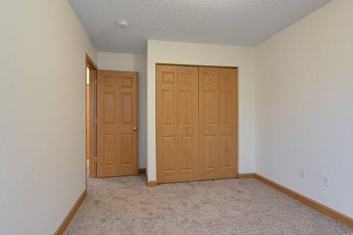 A room with two wooden doors and carpeted flooring.