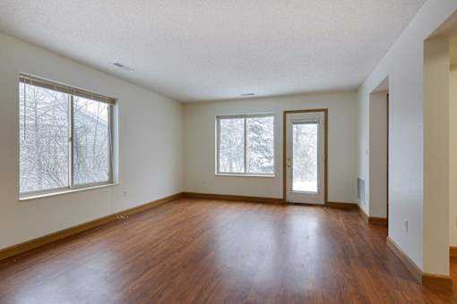 Empty room with wood floors and three windows.