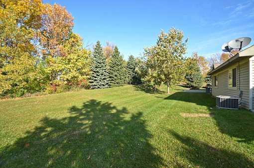 A backyard with a house, trees, and a satellite dish.