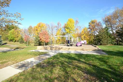 A park with a playground and trees in autumn colors.