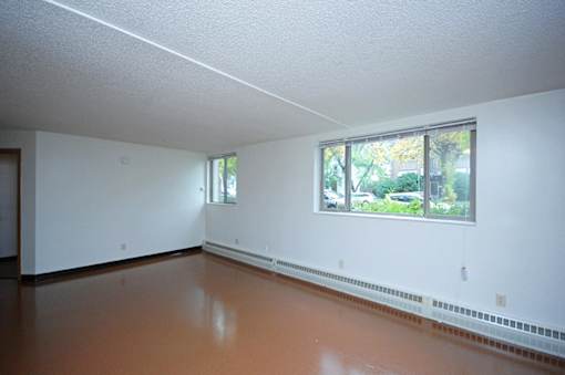 A room with a window and a brown floor.