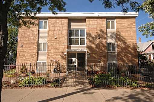 A brown brick building with a black gate in front.