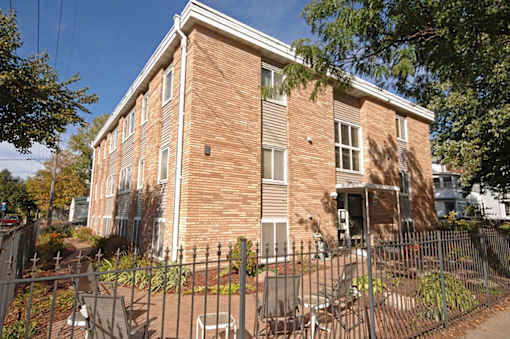 A red brick building with a black fence in front.