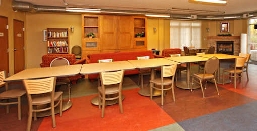 A room with a long table surrounded by chairs.