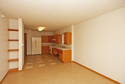 A kitchen with white walls and wooden cabinets.