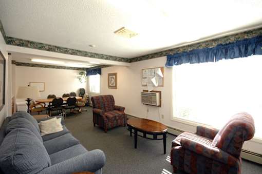 A living room with a grey couch, a red chair and a wooden table.